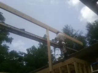 Carpenter setting a ridge beam over a new addition frame — Ice Dam Removal by Roofing Brothers in Pond Creek