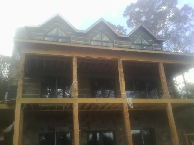 Dormers and porch framing on a large log home under construction — Roof Coating work by our crew in Pond Creek