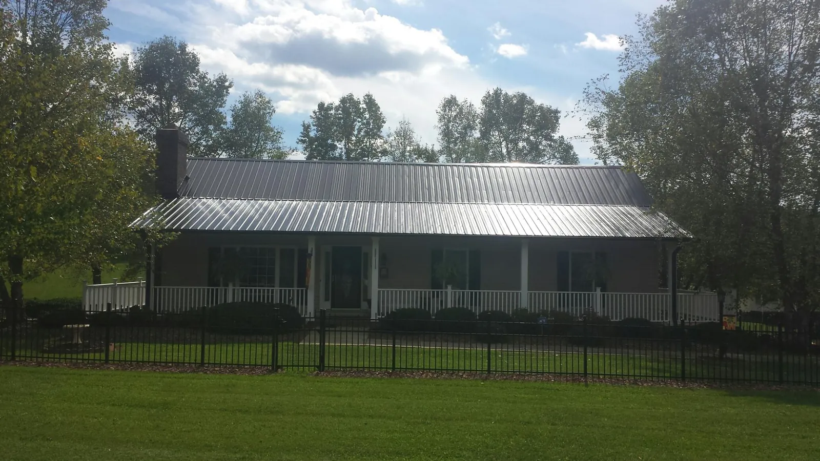 Gray metal roof on a brick ranch with a full width front porch — Gutter Guard Installation work by our crew in Pond Creek