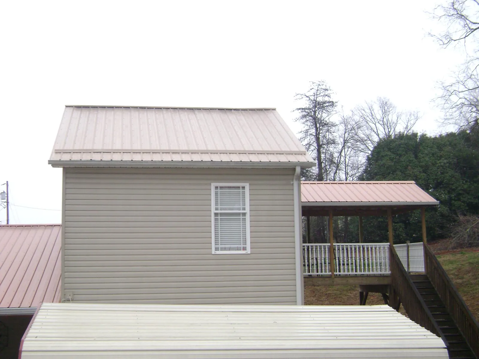 Tan metal roofs on a two story addition and attached porch, from a Roof Replacement job in Pond Creek