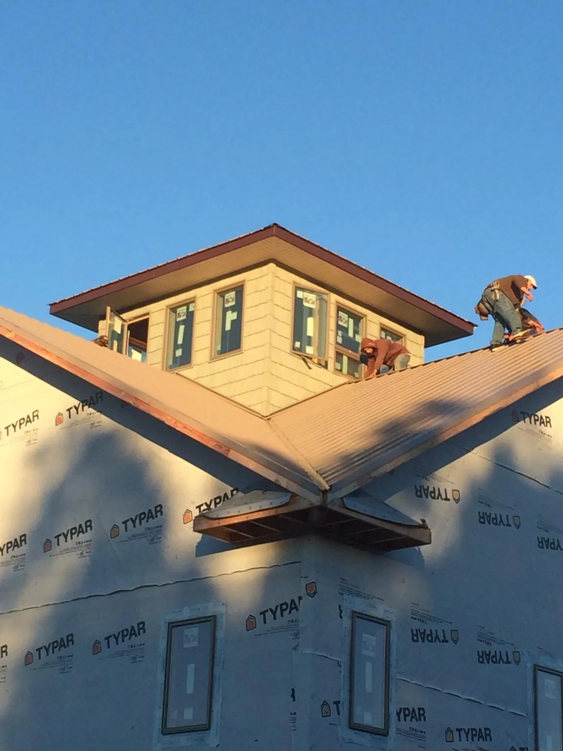 Roofers working around a rooftop cupola on a new metal roof at sunset — Roof Waterproofing in Pond Creek by Roofing Brothers